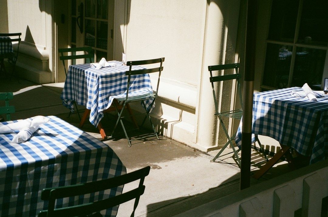Uteservering med blåvitrutiga dukar och svarta bistrostolar