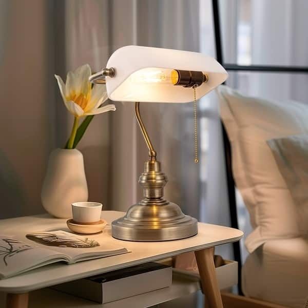 Varmt lysande bordslampa på sängbord intill en fåtölj